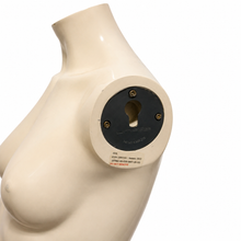 Charger l'image dans la galerie, Close-up of a glossy cream-colored female mannequin torso with a circular black metal panel attached to the back of the neck, showing screws and a small label.