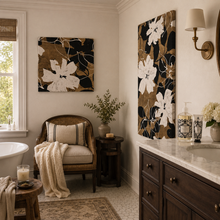 Charger l'image dans la galerie, A styled bathroom interior featuring two vertical floral canvas wall art prints in black, brown, and white. One print is displayed above a wicker armchair with a cream throw blanket, and the other is mounted on the adjacent wall above a dark wood vanity with a white marble countertop.