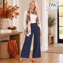Load image into Gallery viewer, A woman models a pair of navy wide-leg pants with a cream ribbed knit top and a colorful patterned scarf in a warm, decorated indoor setting. The Dream Weaver Canada logo is visible in the top right corner.