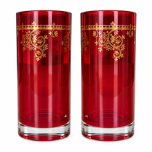 Load image into Gallery viewer, Two tall red glass tumblers with ornate gold floral scrollwork bands near the top, shown side by side on a white background.