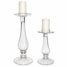 Load image into Gallery viewer, Two clear glass candlestick holders with white pillar candles, shown on a plain white background.