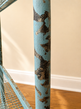 Charger l'image dans la galerie, A close-up of a distressed light blue painted wooden pole with peeling paint revealing brown wood underneath, standing in an indoor room with a beige wall, white baseboard, and wood floor.
