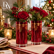 Load image into Gallery viewer, Two tall red glass vases with gold decorative bands, filled with red roses, green foliage, and red berries, displayed on a decorated holiday table.
