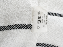 Load image into Gallery viewer, Close-up of a white woven textile with black striped pattern and a sewn-on care label reading MADE IN INDIA.
